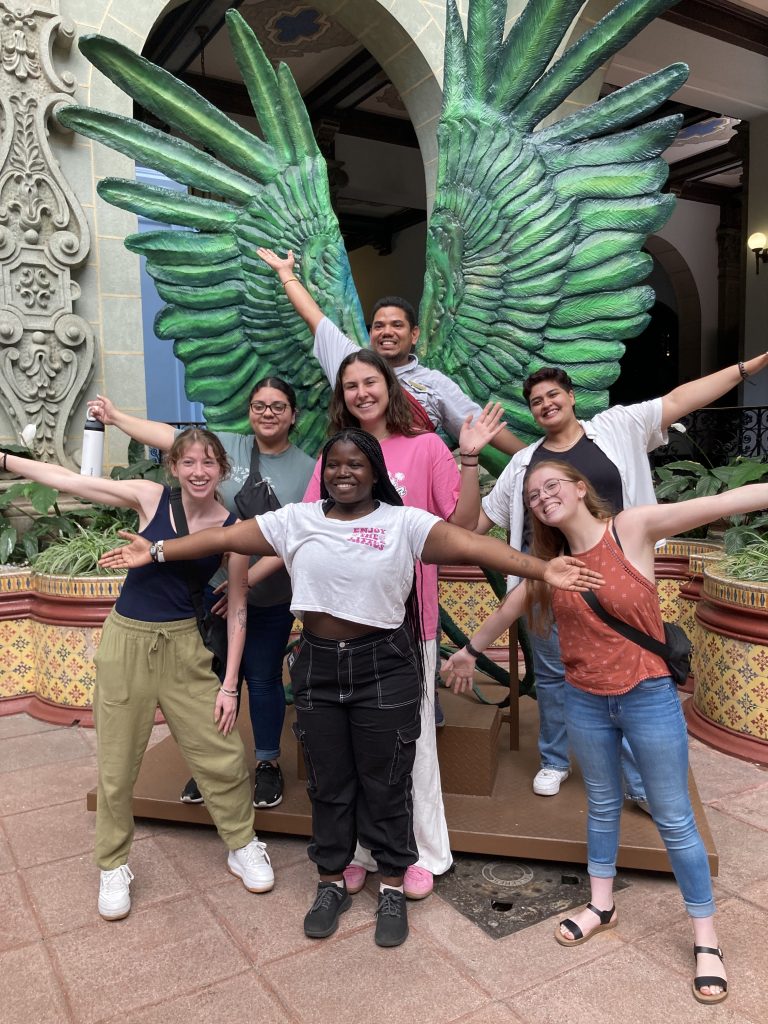SST students in Guatemala posing in front of a winged scupture