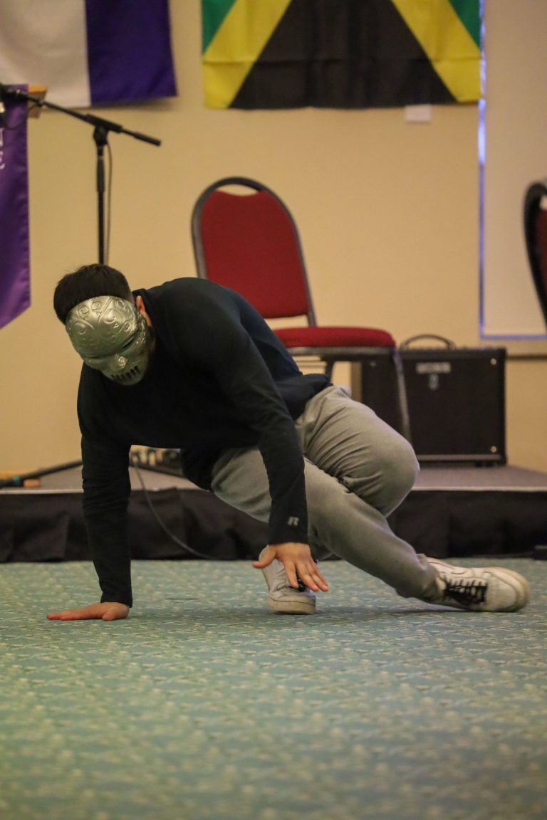 masked student spinning on the ground balancing on his hands