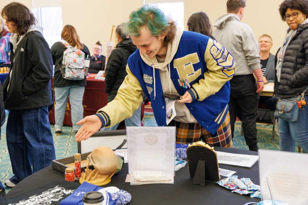 Student rolls dice at Goshen and Dragons booth.
