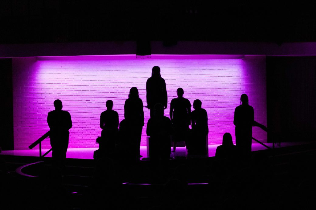 silhouettes of many people against purple background
