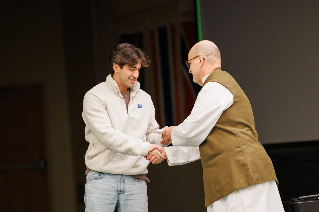 Man giving award to another man.
