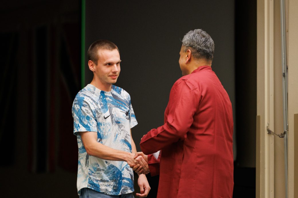 Man giving award to another man.
