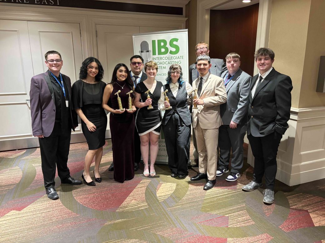 students pose in front of banner that reads "IBS"