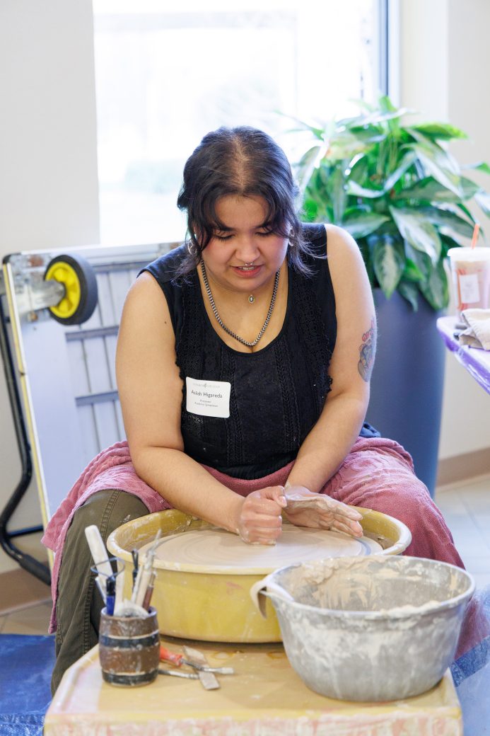 Student throwing clay on wheel