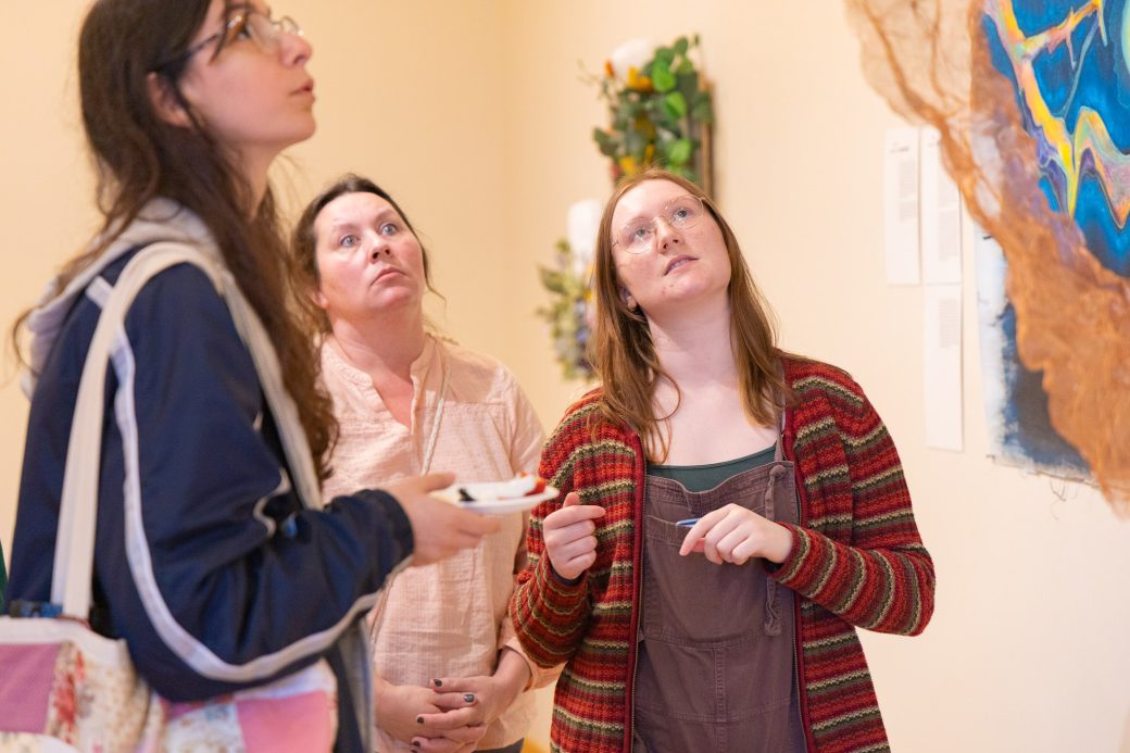 Three students looking up at artwork