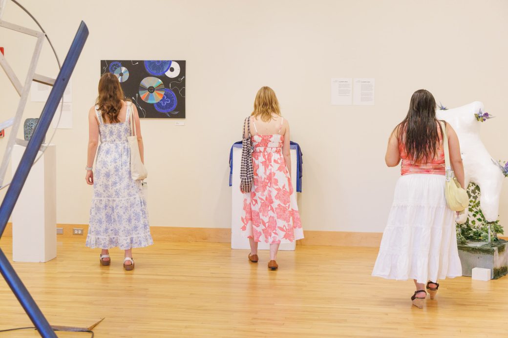 Three students looking at three different artworks