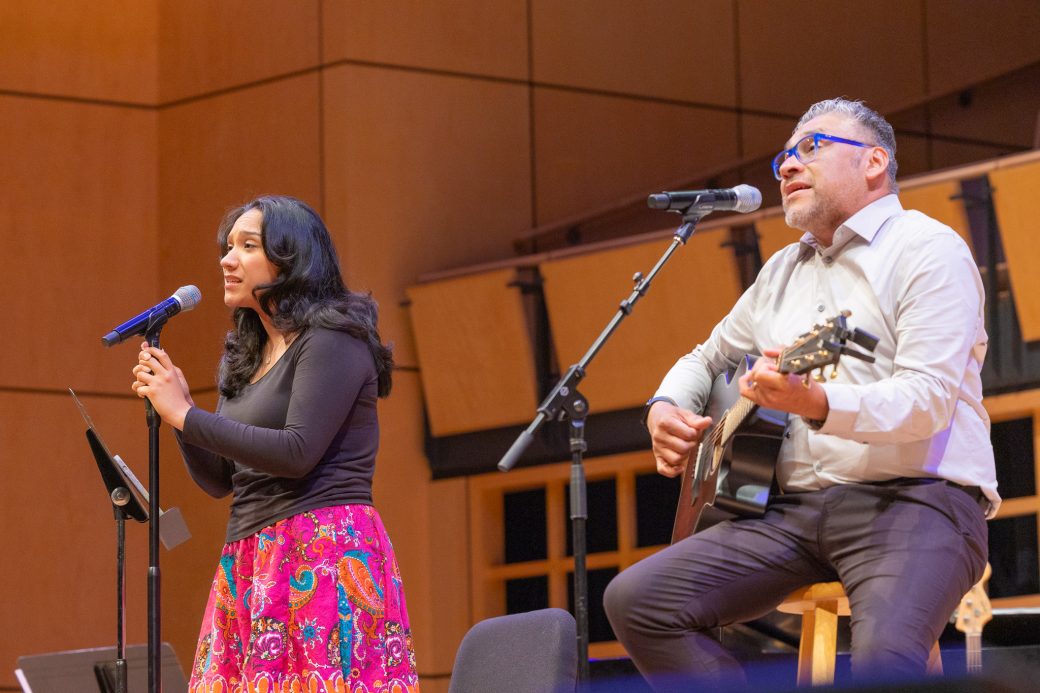 Father and daughter sing and play guitar in a duet