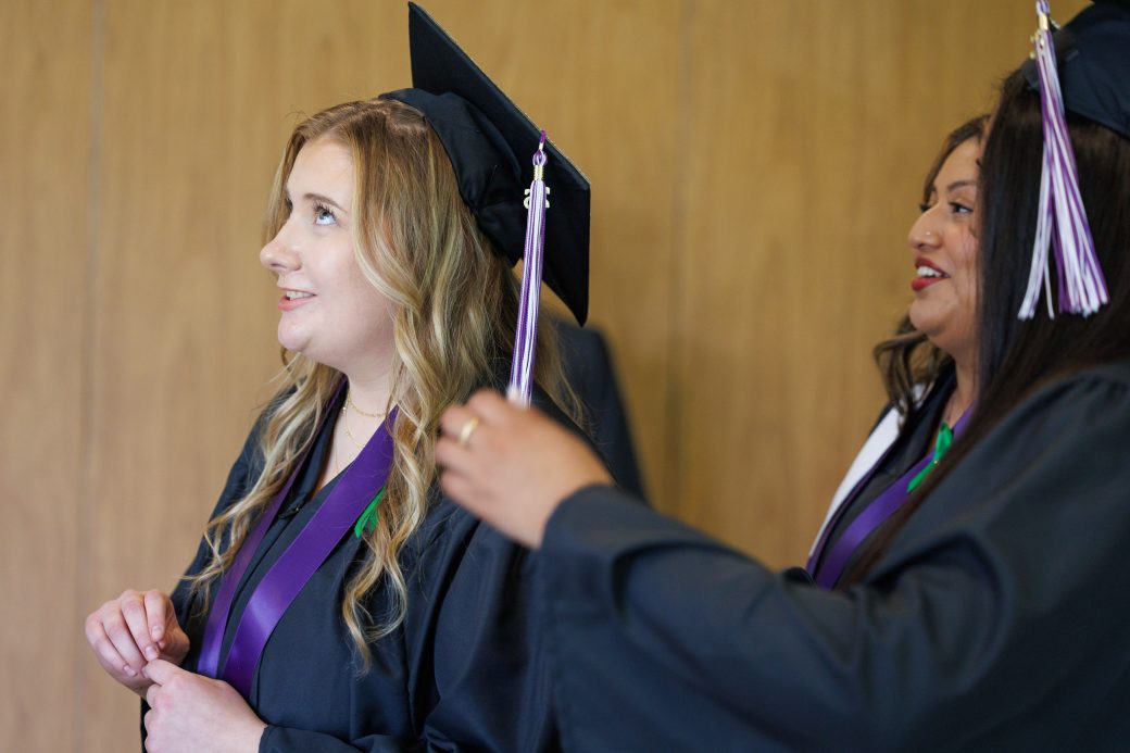 Female graduate helping another female graduate with cap