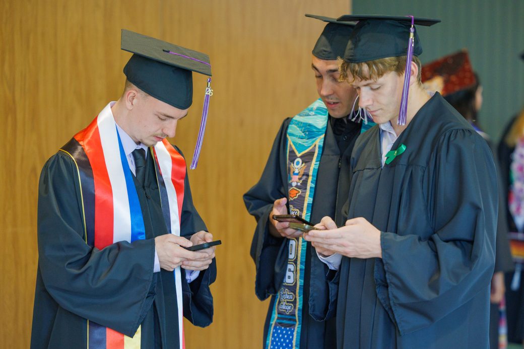 Three male graduates in a group texting
