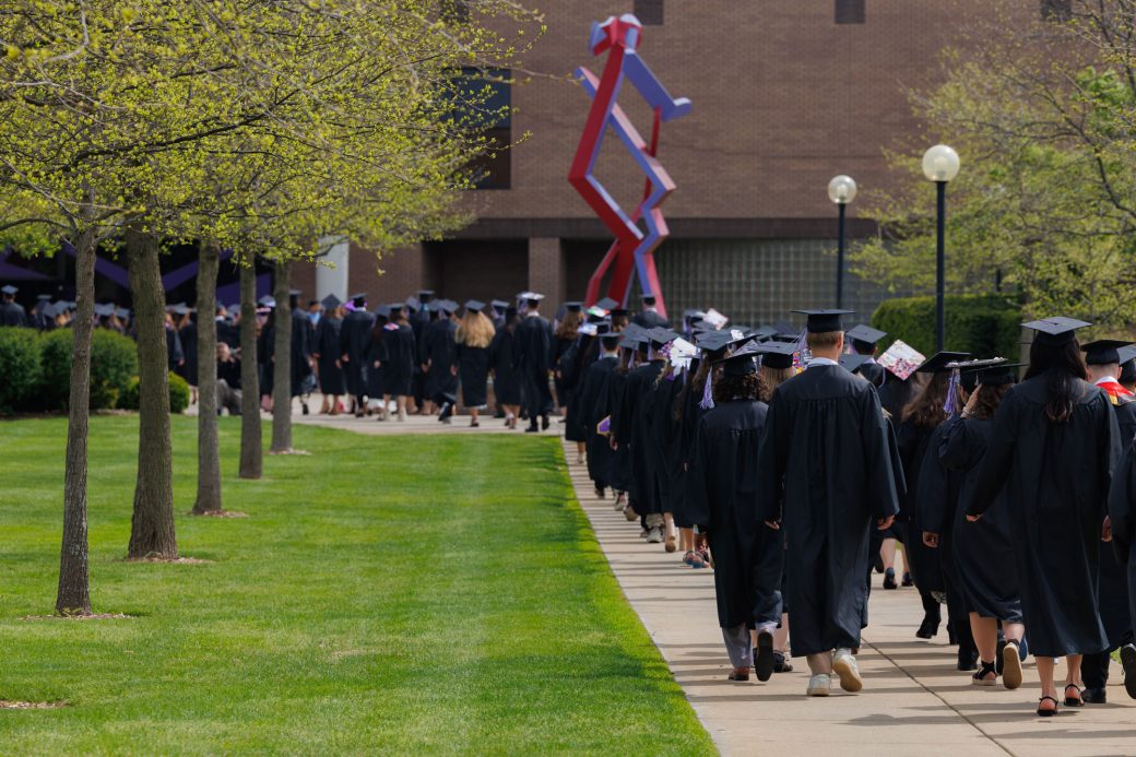 Graduates walk on sidewalk toward the Roman Gingerich Recreation-Fitness Center