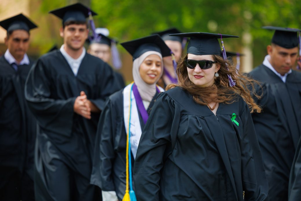 Female graduate walking with sunglasses