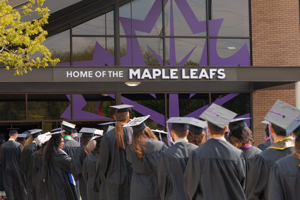 Group of graduates lined up outside of Home of the Maple Leafs sign