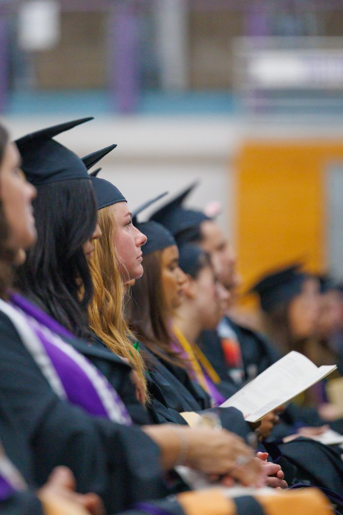 Close-up of graduate seated and looking toward the stage during commencement
