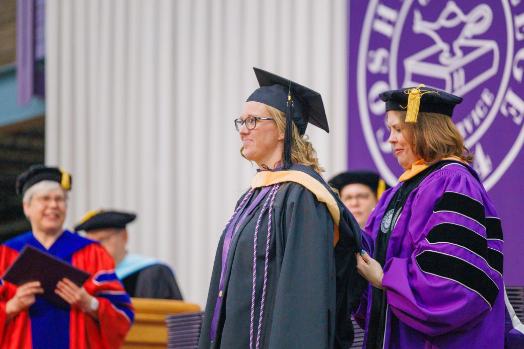 Smiling female graduate getting sash placed