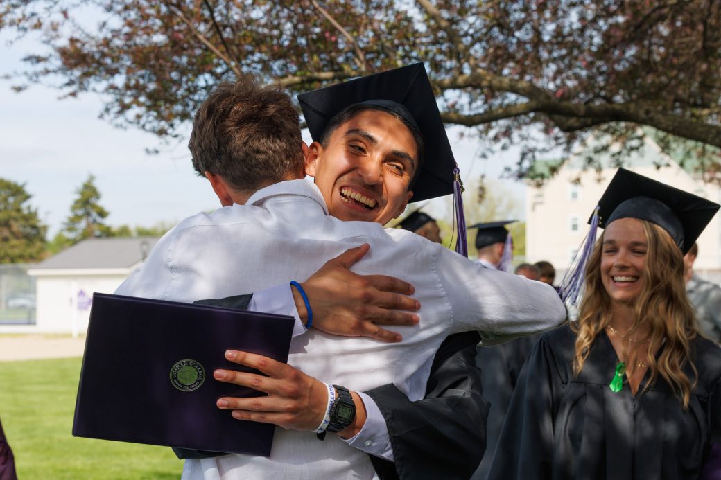 Graduate hugging friend with diploma in hand