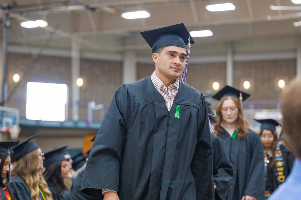 Male graduate walking by heading to get dipoma