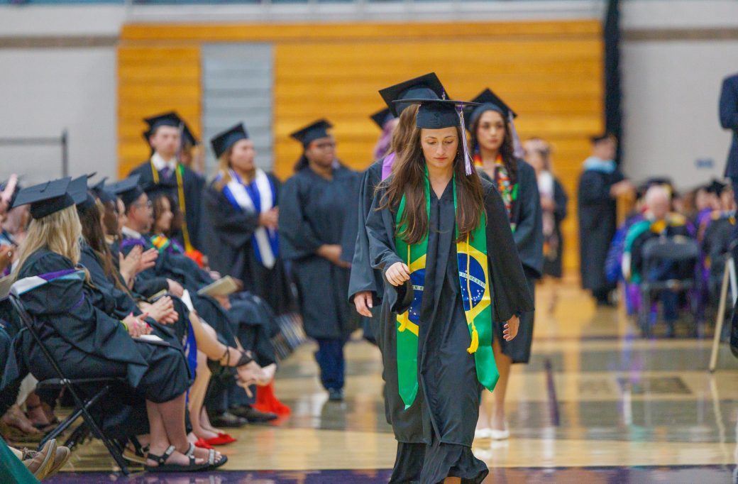 Graduate walking with Brazilian flag decorated stole