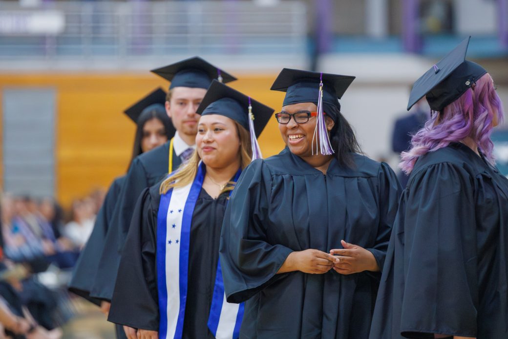 Female graduate looking on to family with smile