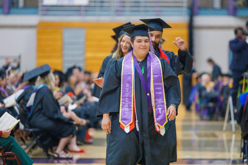 Long line of graduates walking toward stage for diploma
