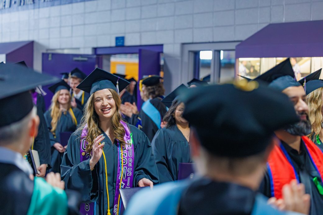 Graduates walking out between applauding faculty and staff after ceremony