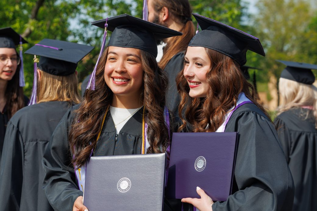 Two graduates posing with diplomas