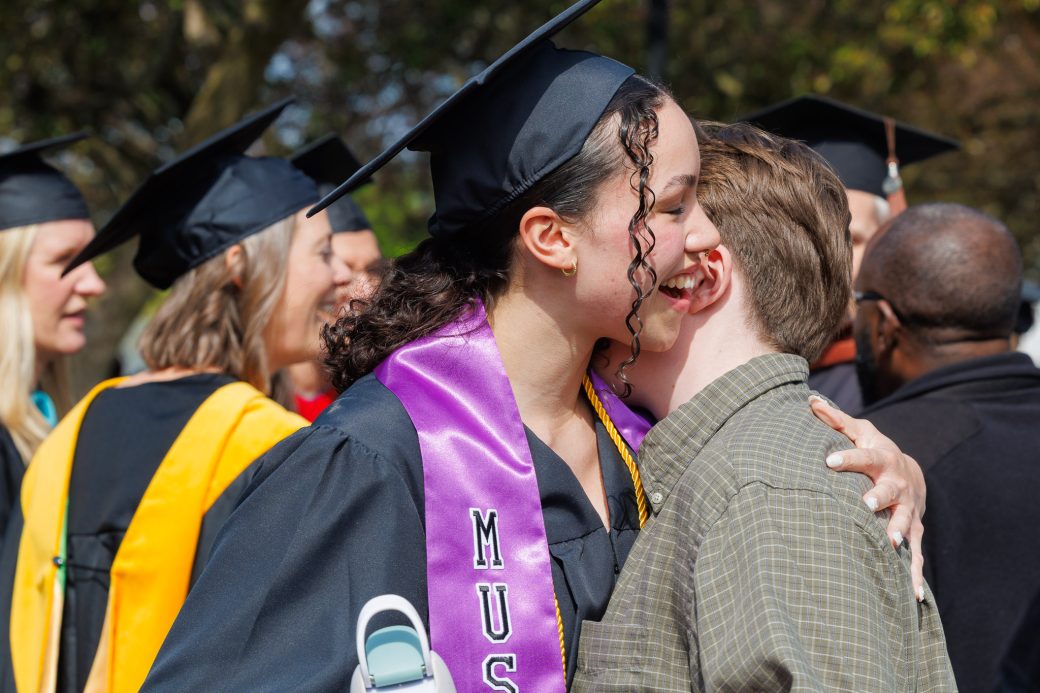 Graduate hugging family and friends outside after commencement