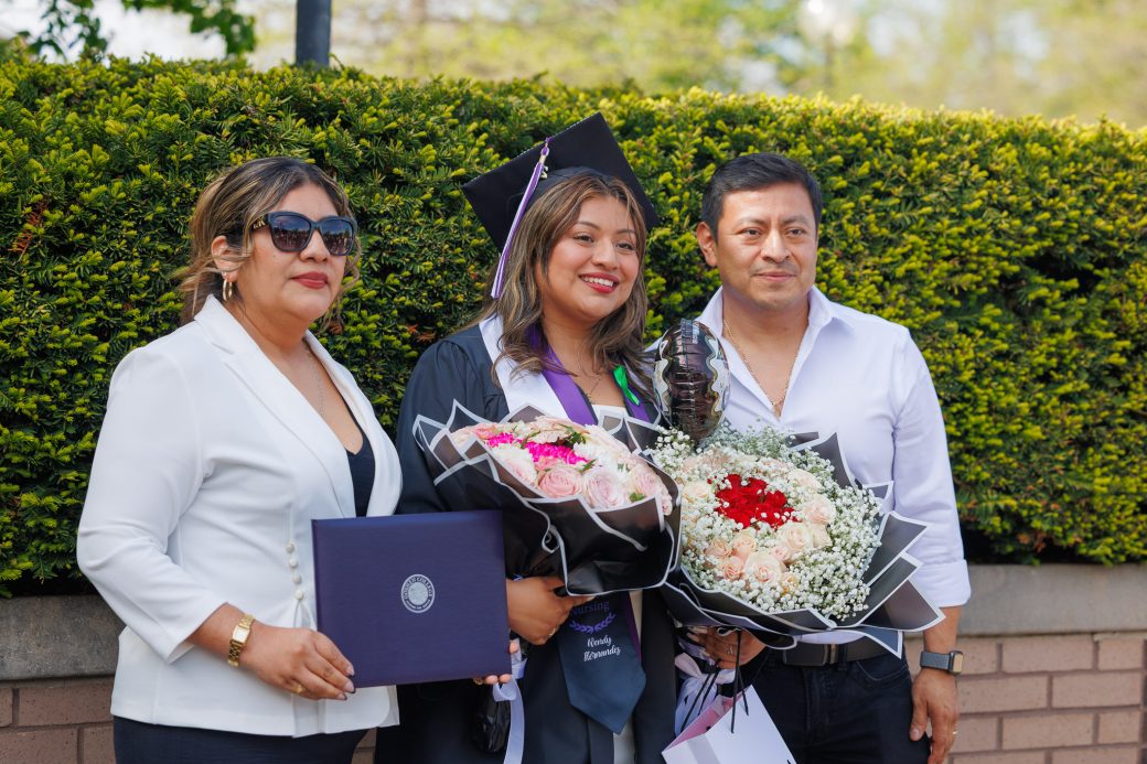 Graduate holding bouquet of flowers with family