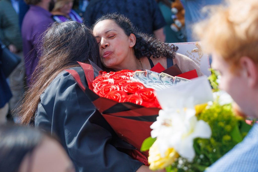 Graduate hugging mom with bouquet of roses