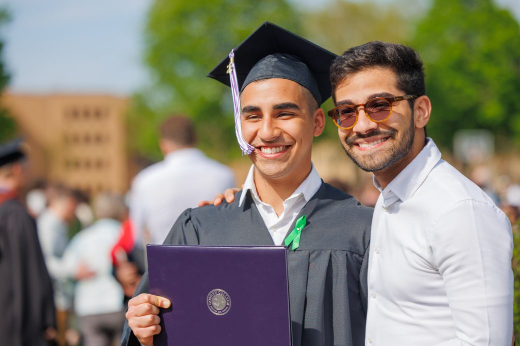 Graduate and family member posed with diploma smiling