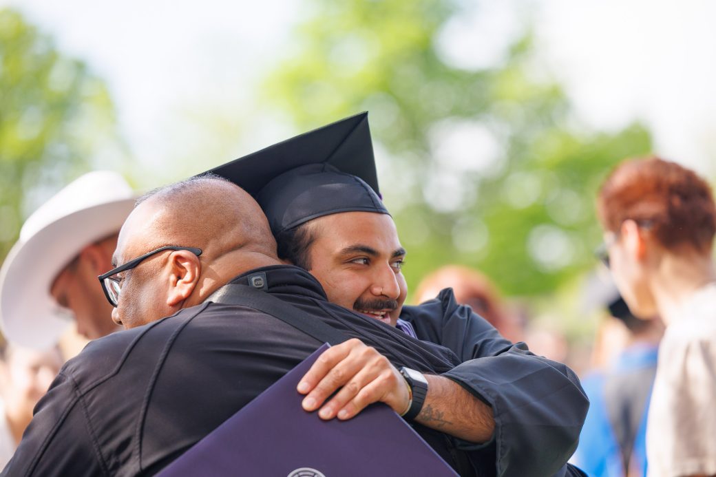 Graduate embracing loved ones outdoors following graduation ceremony