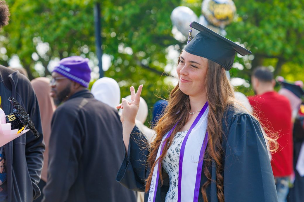Graduate giving peace sign to friend