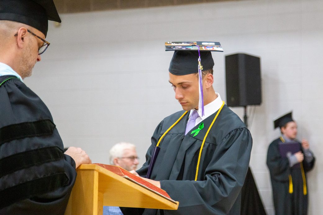 Graduate signs book after receiving diploma