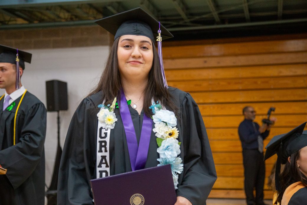 Graduate smiling softly while holding diploma