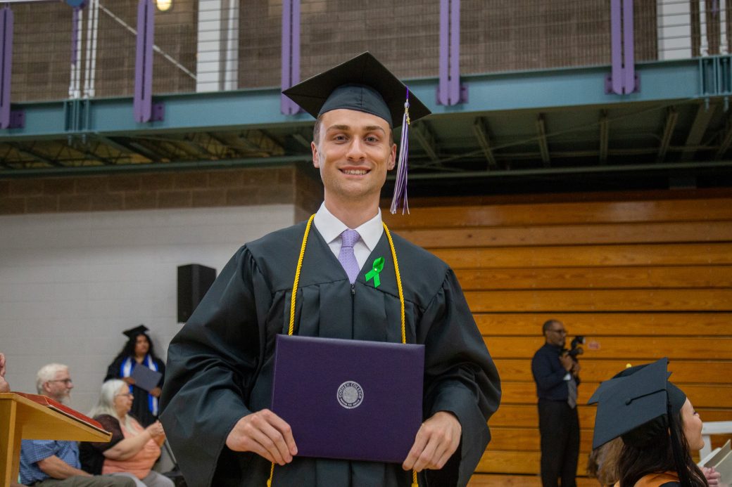 Graduate standing confidently while holding diploma