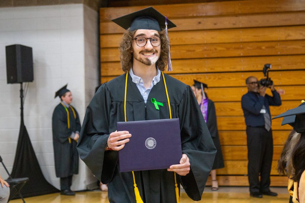 Graduate smiling with diploma after exiting the stage