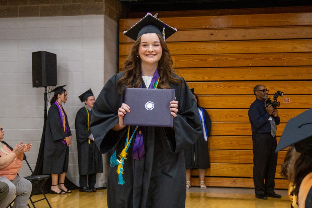 Graduate smiling broadly while holding diploma
