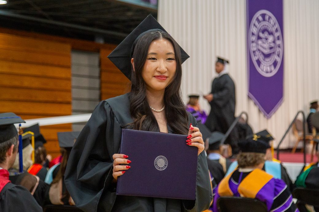 Graduate looking off camera holding diploma