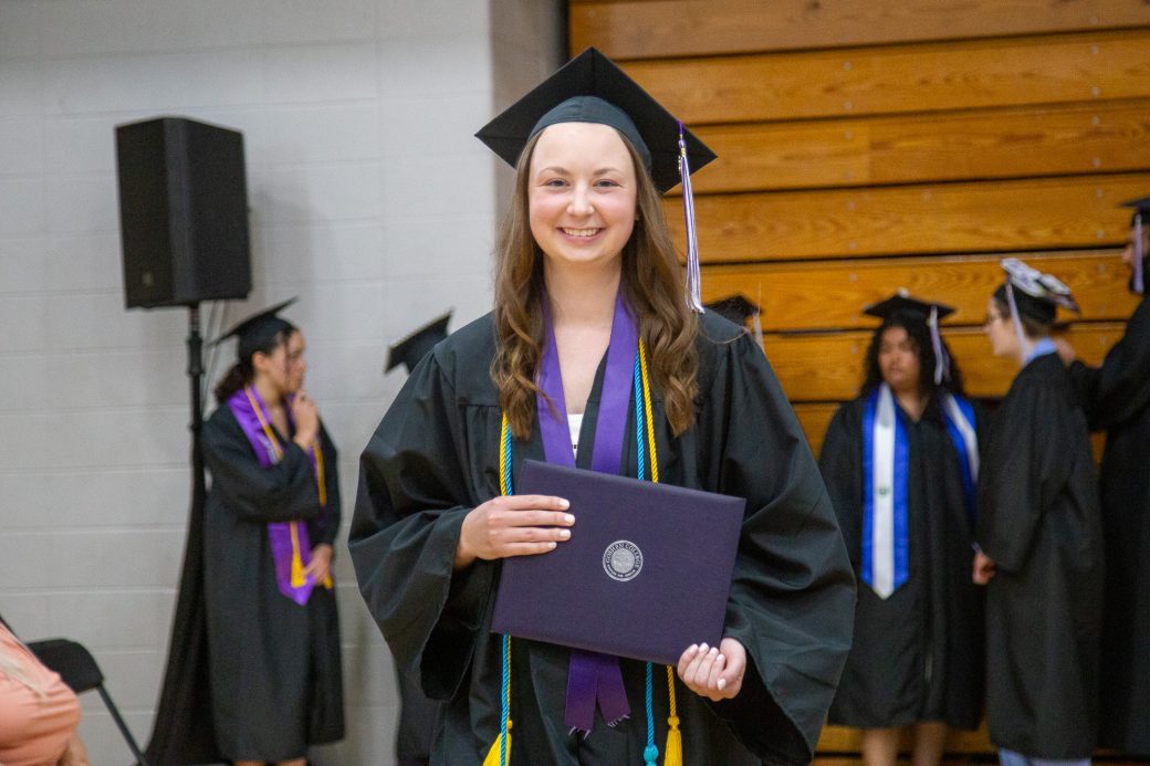 Graduate holding diploma after getting off stage