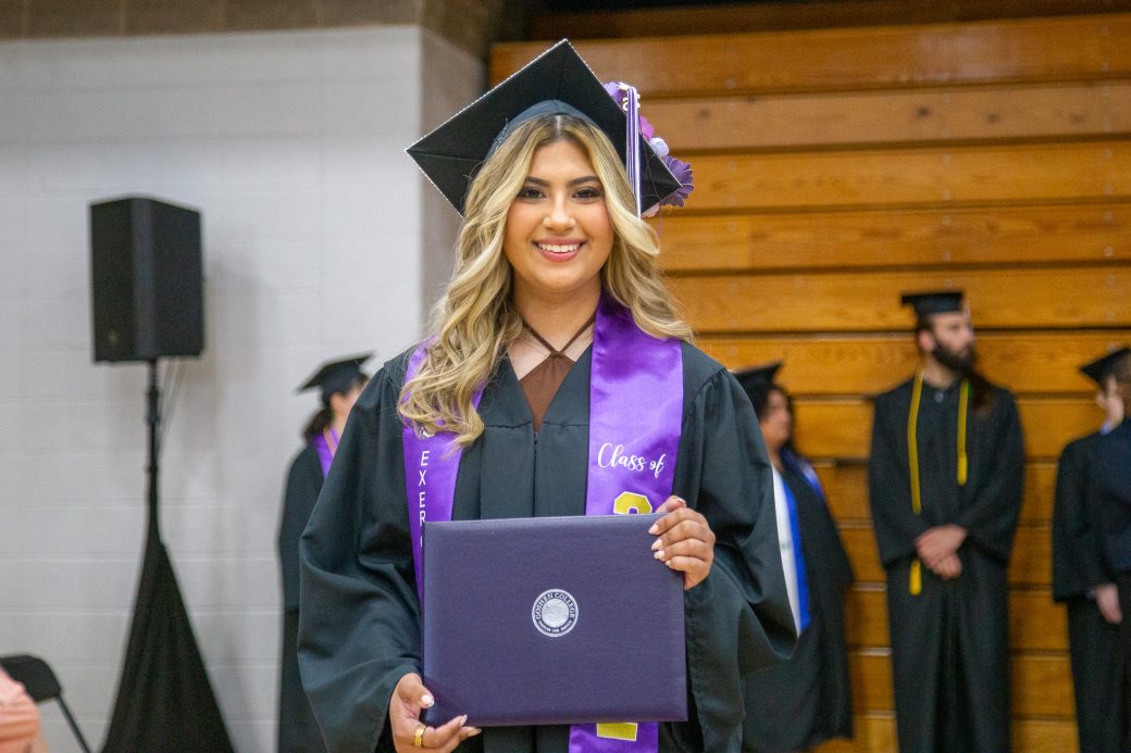 Graduate smiling holding diploma with both hands