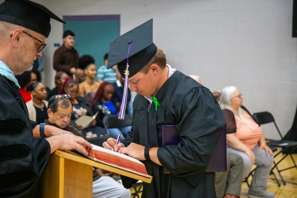 Graduate writing in graduation record book after ceremony