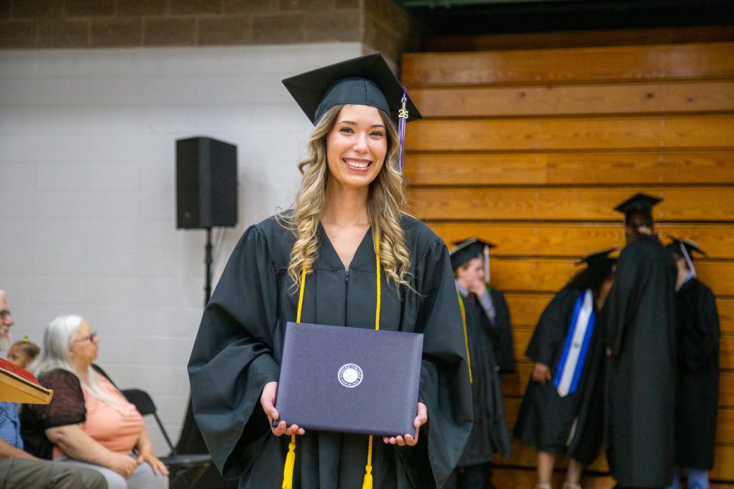 Graduate posing with diploma shortly after receiving it