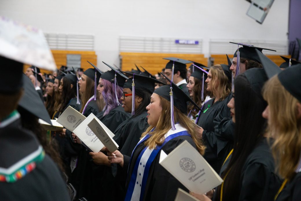 Students standing together and singing during graduation benediction