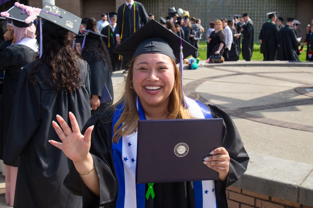 Graduate waving while holding diploma