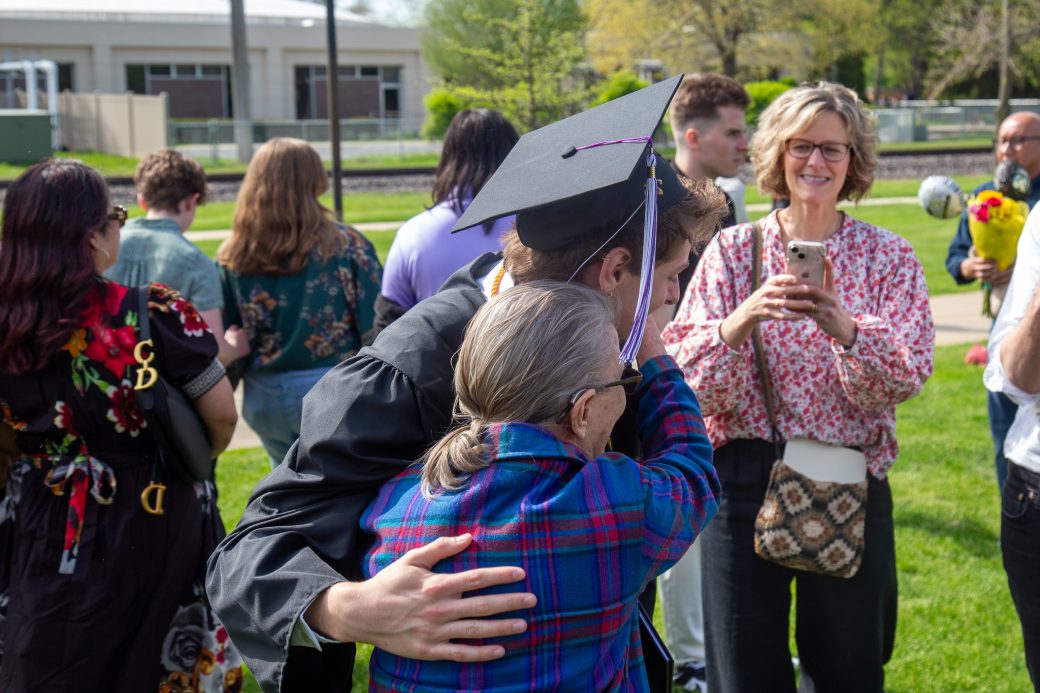 Graduate celebrating with hugs from family and friends outside