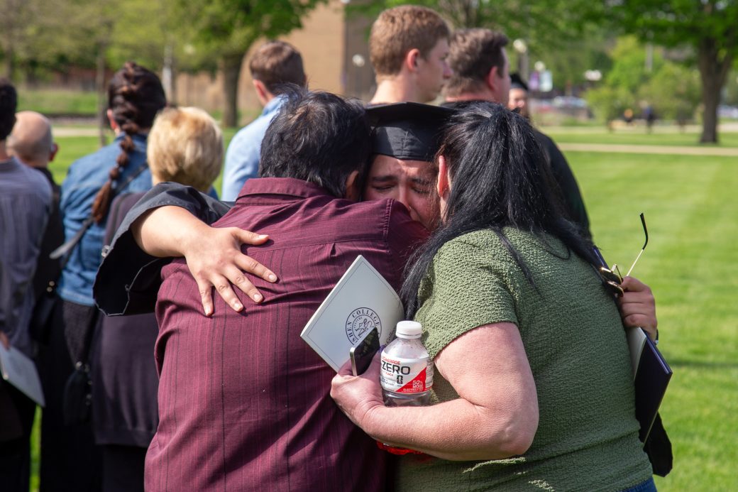 Graduate hugging loved ones outside ceremony venue