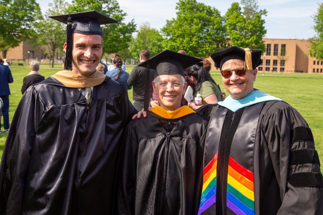 Graduate smiling with supporters on campus after receiving diploma