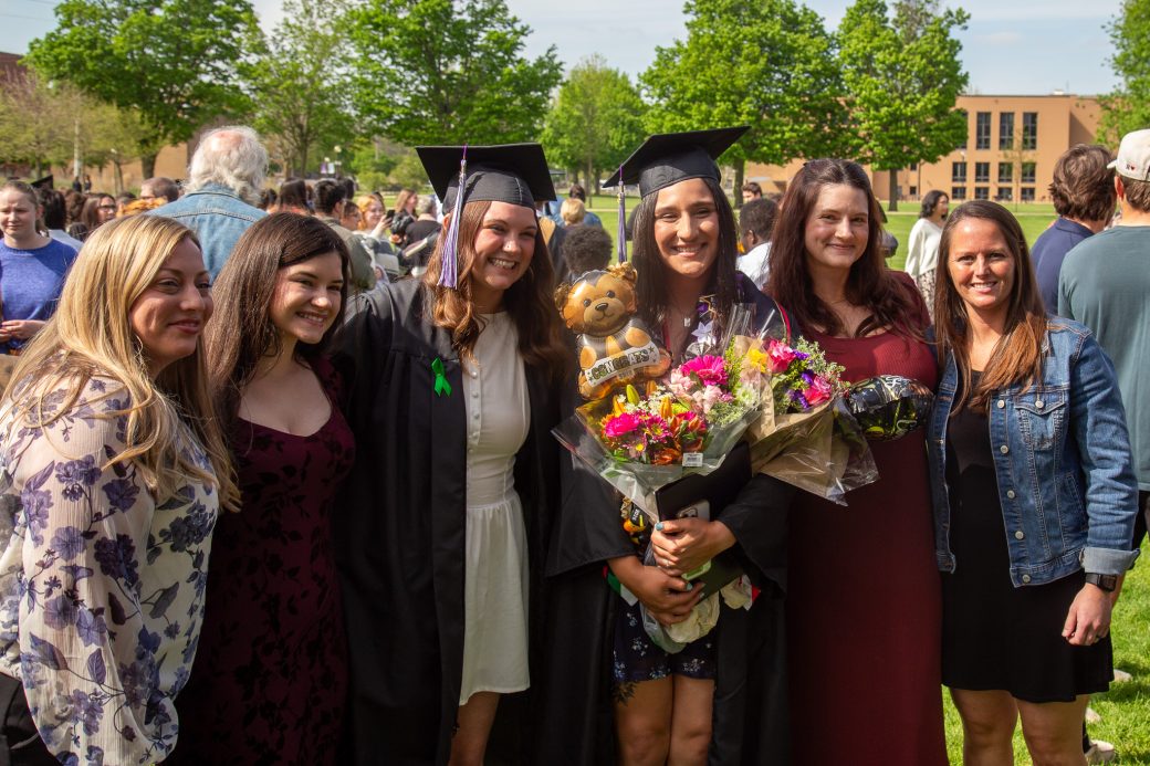 Graduate posing with family and friends outside after commencement
