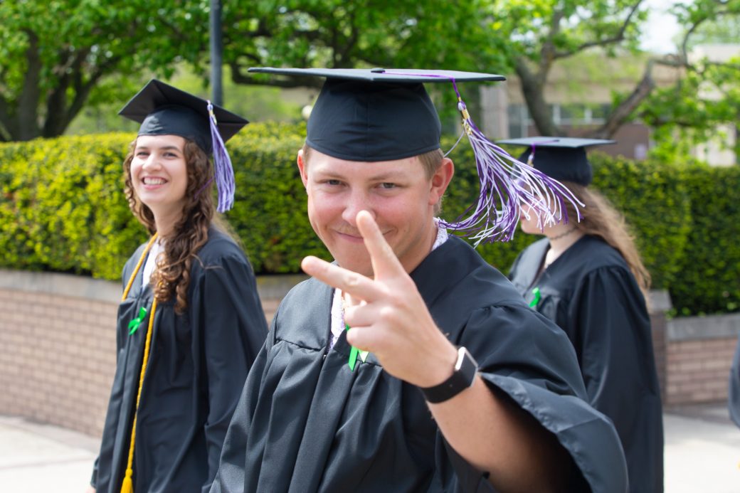 male graduate giving peace sign