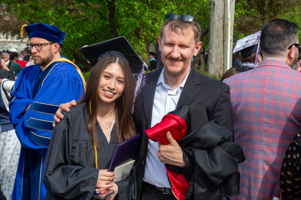 Graduate posed with faculty and staff after ceremony