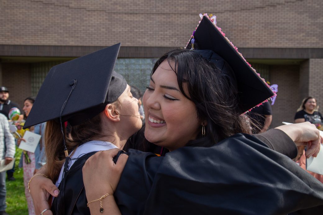 Graduate surrounded by hugs from family and friends outdoors